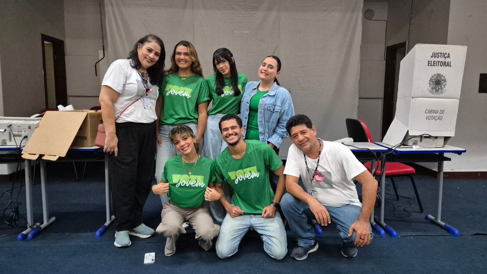 Grupo de alunos do Colégio Thales de Azevedo e servidores do TRE-BA se reunem sorrindo para foto em auditório.