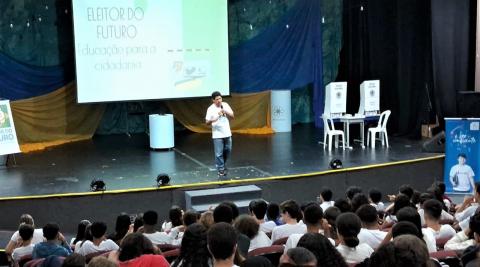 Servidor Silas Gomes no palco do Colégio Maristas apresentando o Projeto Eleitor do Futuro