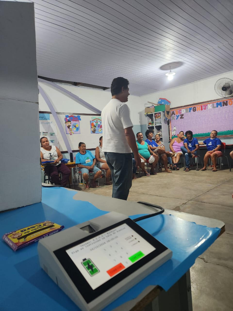 Servidor Silas se apresentando no EJAI. Microterminal do eleitor no primeiro plano.