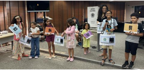 Pra todos verem: crianças enfileiradas lado a lado, meninas e meninos de diferentes idades. 
